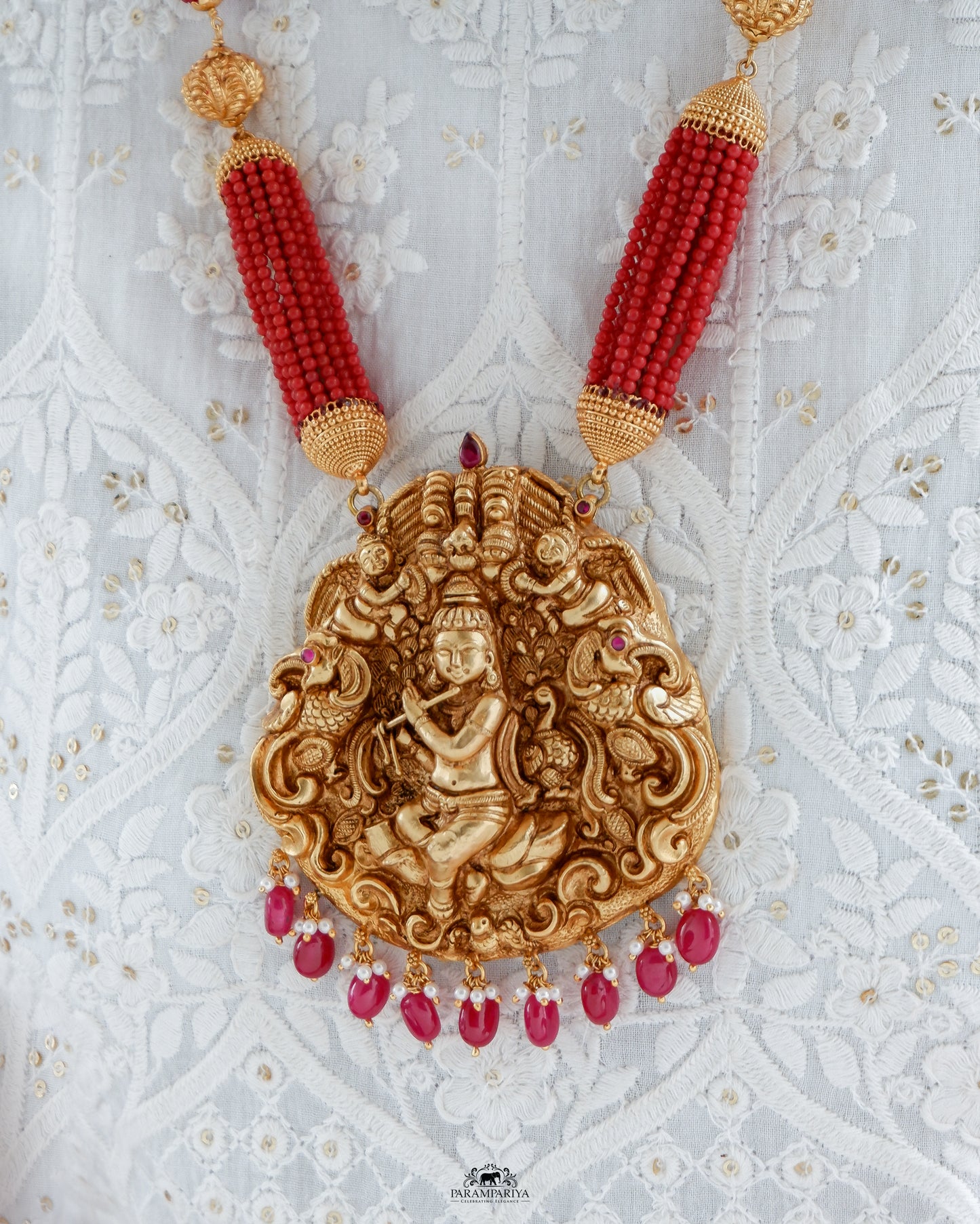 Uncover an artfully crafted unisex necklace adorned with an intricate charm of Lord Krishna and corals on www.parampariya.in. This exquisite jewel is made from pure silver and plated with antique gold microns for a beautiful finish.