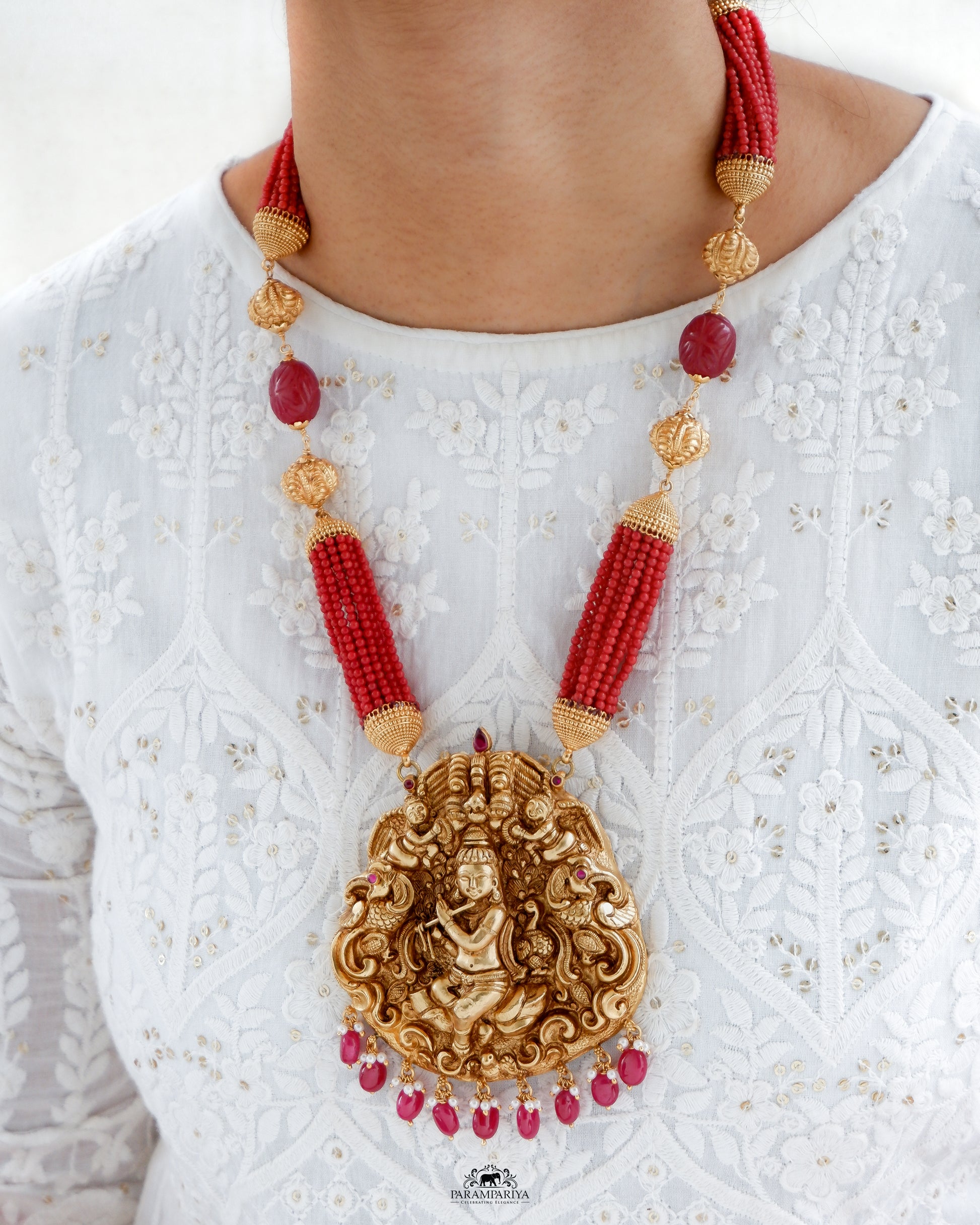 Uncover an artfully crafted unisex necklace adorned with an intricate charm of Lord Krishna and corals on www.parampariya.in. This exquisite jewel is made from pure silver and plated with antique gold microns for a beautiful finish.