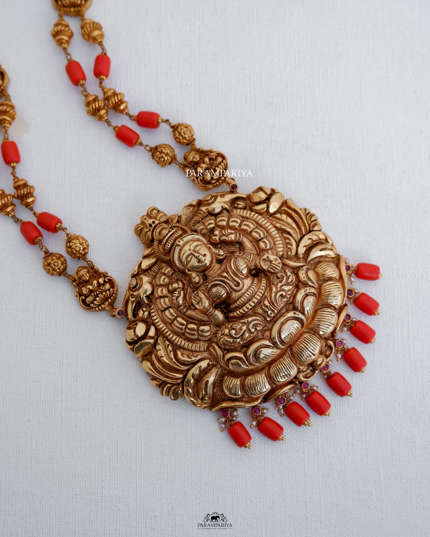 This temple necklace features a depiction of goddess Lakshmi, precisely hnadcrafted with pure silver and adorned with micron gold plating and coral semi-precious beads.